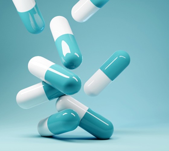 3D illustration of teal and white pills tumbling