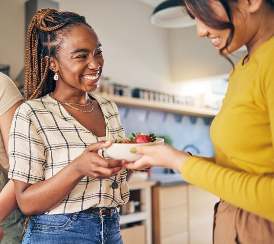 Group of friends smiling while preparing meal together in kitchen