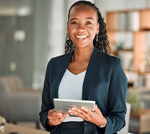 Woman smiling while holding tablet in office