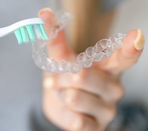 Patient using toothbrush to clean aligner