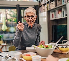 Woman smiling while eating in kitchen with friend