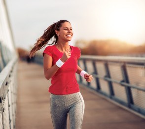 Woman smiling while running on bridge