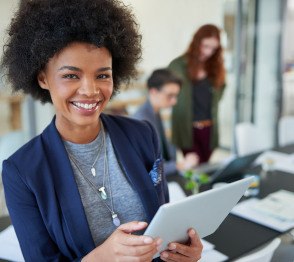 Woman smiling while holding tablet in office