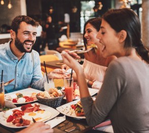 Group of friends smiling while eating lunch at restaurant