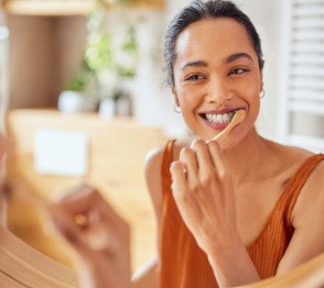 Woman smiling while brushing her teeth