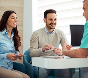 Dentist and couple talking in dental office