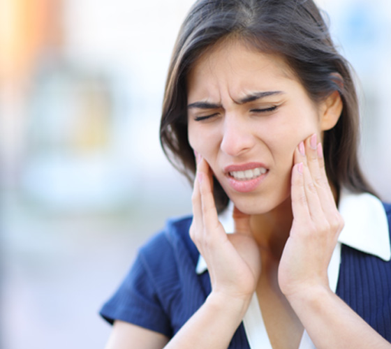 a woman holding her jaw in pain