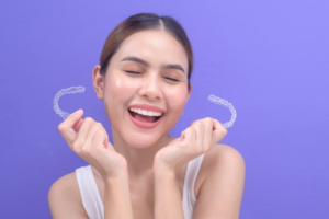 Woman smiling in excitement while holding her Invisalign trays